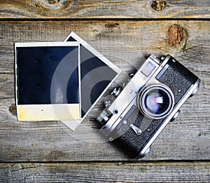 Vintage camera with lenses and blank old photograph on wooden background