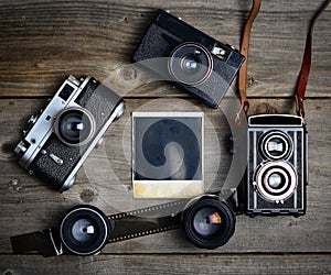 Vintage camera with lenses and blank old photograph on wooden background