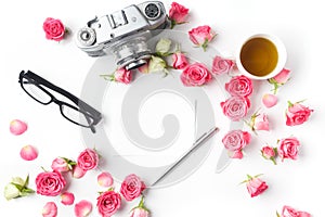 Vintage camera pink roses and note on white background. Flat lay. Top view