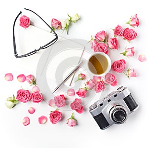 Vintage camera pink roses and note on white background. Flat lay. Top view