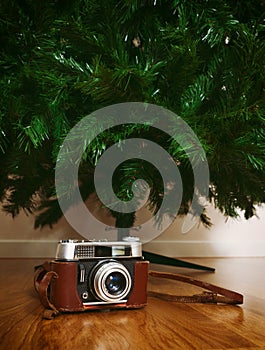 Vintage camera under bare artificial christmas tree