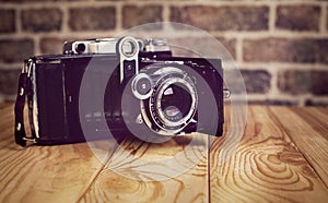 Vintage camera on wooden and brick background