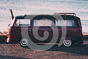 A vintage camper van parked near the sea at sunset