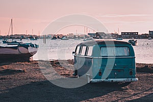 A vintage camper van parked near the sea at sunset
