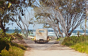 Vintage car parked in beach access with view of sea through rear window photo