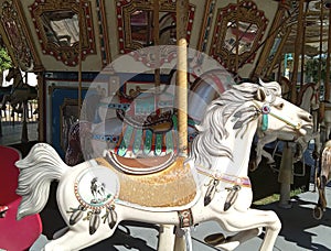 Vintage Carousel with white horse glowing in the sunlight