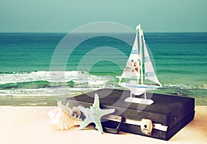 Vintage case with old boat toy and starfish in front of seascape. travel concept. filtered image.