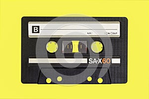 Vintage cassette tape isolated. Black audio cassette B side on yellow background.