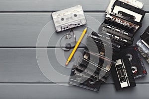 Vintage cassettes and pencil to rewind tape on gray wooden background