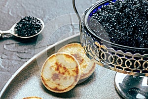 Vintage caviar dish with black caviar and blinis, a closeup on black