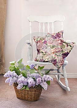 Vintage chair with bouquet of lilac in basket