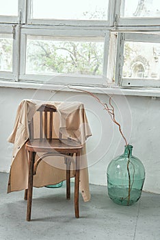 a vintage chair with a sand-colored jacket thrown over it in a room with rough white walls