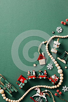 Vintage Christmas flat lay composition with wooden handmade toys and garland on green background