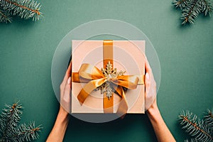 Vintage Christmas gift box with golden ribbon bow and snowflake on dark green background with fir tree branches. Retro style Xmas