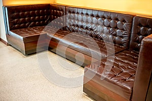 Vintage classic brown leather sofa on white floor against yellow