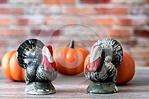 Vintage clay turkeys with orange pumpkins colorful autumn leaves. Seasonal display for Thanksgiving and Halloween