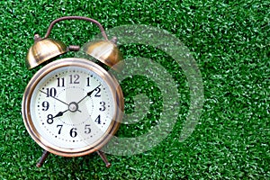 Vintage clock on artificial grass floor. Time concept