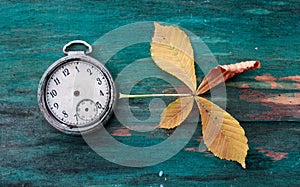 vintage clock and autumn leaf on wood background