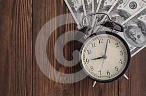 A vintage clock and money against a natural tree background. Tim