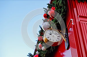 Vintage clock in the street decorated with fir branches, red and white baubles