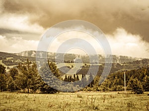 Vintage cloudy misty mountain ladscape, meadow and forest