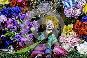 Vintage clown doll on green grass and spring flowers