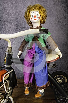 Vintage clown doll sitting on antique tricycle