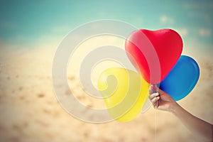 Vintage color tone balloon heart shape in hand on sea sand beach summer day and nature background