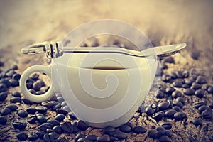 Vintage color tone, coffee cup with spoon and beans on the old wooden background