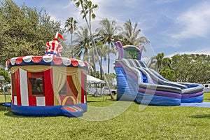 Vintage colorful small gazebo bounce house inflated next to a large blue twin falls inflated kids slip and slide