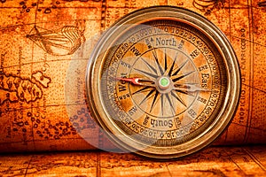 Vintage compass lies on an ancient world map.