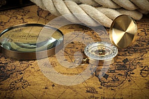 Vintage Compass and magnifying glass lies on an ancient world map - adventure stories background