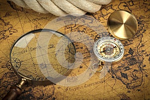 Vintage Compass and magnifying glass lies on an ancient world map - adventure stories background