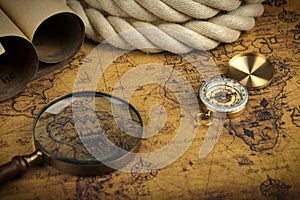 Vintage Compass and magnifying glass lies on an ancient world map - adventure stories background