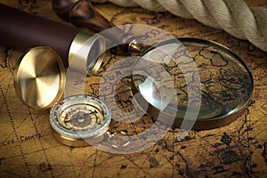 Vintage Compass and magnifying glass lies on an ancient world map - adventure stories background