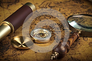 Vintage Compass and magnifying glass lies on an ancient world map - adventure stories background