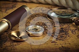 Vintage Compass and magnifying glass lies on an ancient world map - adventure stories background