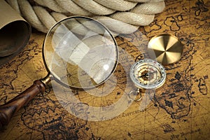 Vintage Compass and magnifying glass lies on an ancient world map - adventure stories background