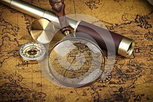 Vintage Compass, magnifying glass and spyglass telescope lies on an ancient world map - adventure stories background