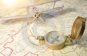 A vintage compass on the map and an airplane in the background.