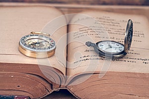 Vintage Compass and pocket watch on books.