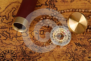 Vintage compass with spyglass telescope and cinnamon spices on an old world map - trade and explorer concept