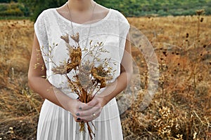 Vintage concept with a young woman holding a bouquet of dry flow