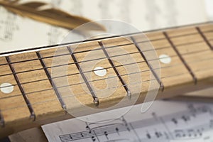 conceptual composition of notes, wooden guitar and sound board a golden bird`s feather is on a sheet of old yellowed and