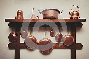 Vintage copper cookware collection on wooden shelf