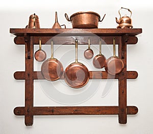 Vintage copper cookware hung on wooden shelf