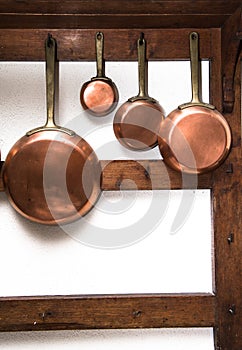 Vintage copper pans hung on wooden shelf