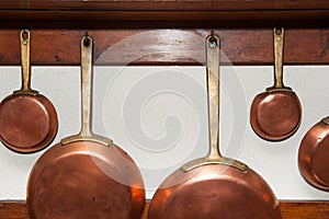 Vintage copper pans hung on wooden shelf