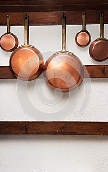 Vintage copper pans hung on wooden shelf