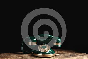 Vintage corded phone on table against black background. Space for text